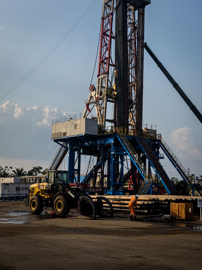 Oil rig in action during sunset, featuring heavy machinery and a lone worker on site.